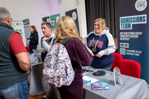 University Open Day pop-up banner and stand, with new University staff members talking to two prospective students