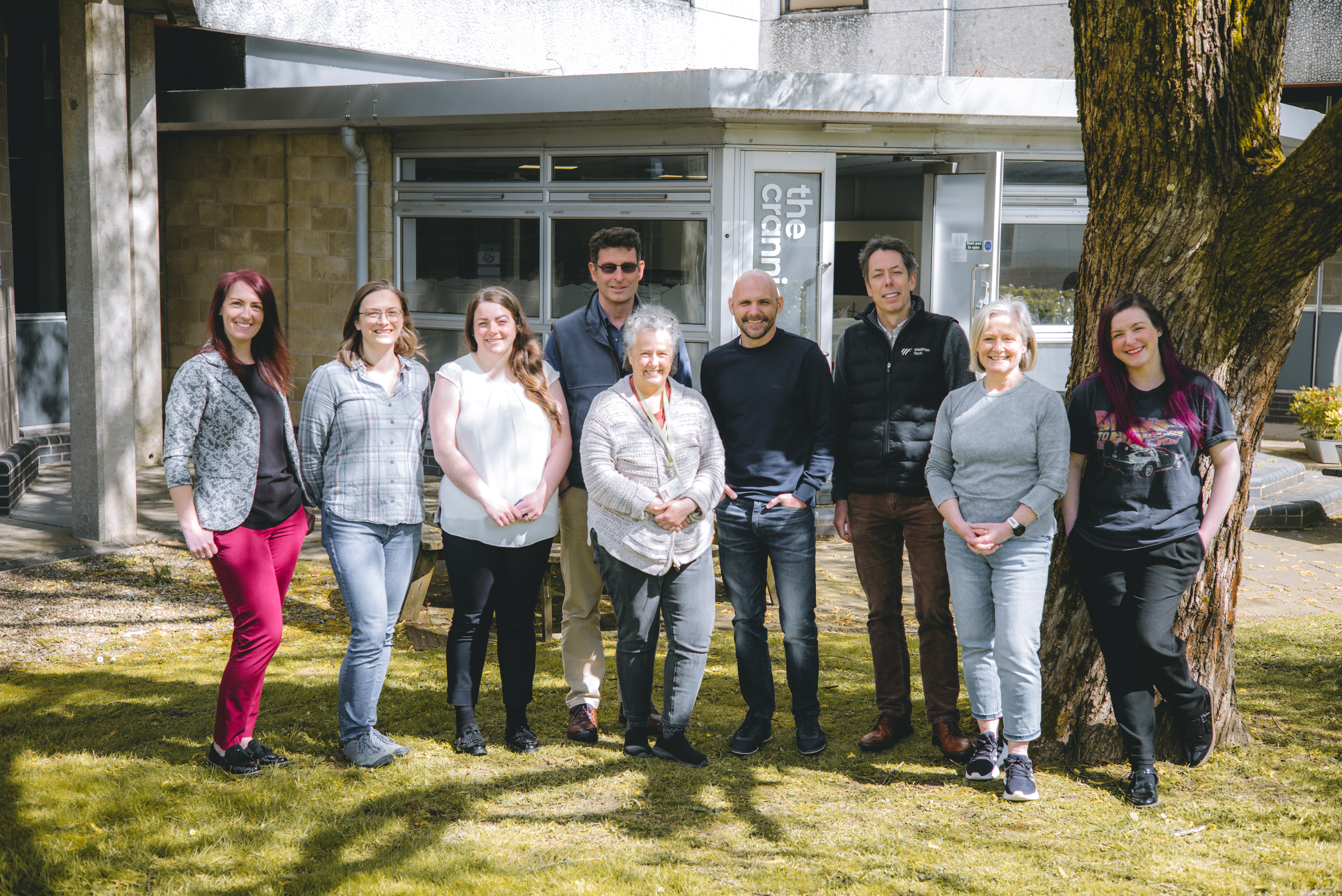 Image of nine members of the WellFish Tech team, pictured outside the WellFish Tech offices