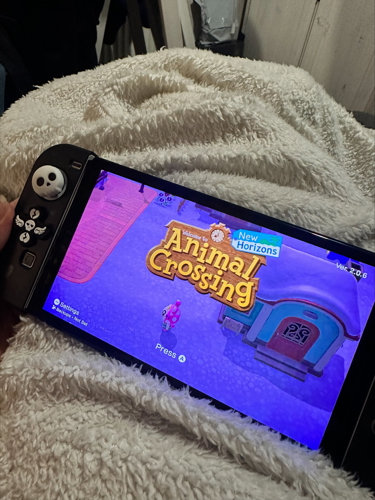 'Animal Crossing' game displayed on a black Nintendo Switch, placed on top of a white blanket