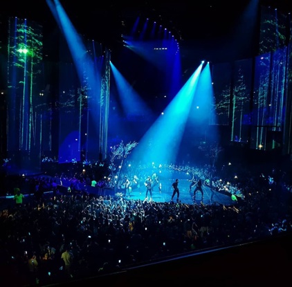 Interior of The OVO Hydro music arena with a music performer on the stage surrounded by crowds of people