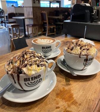 Three cups of coffee on a table in 'Blend' branded coffee cups